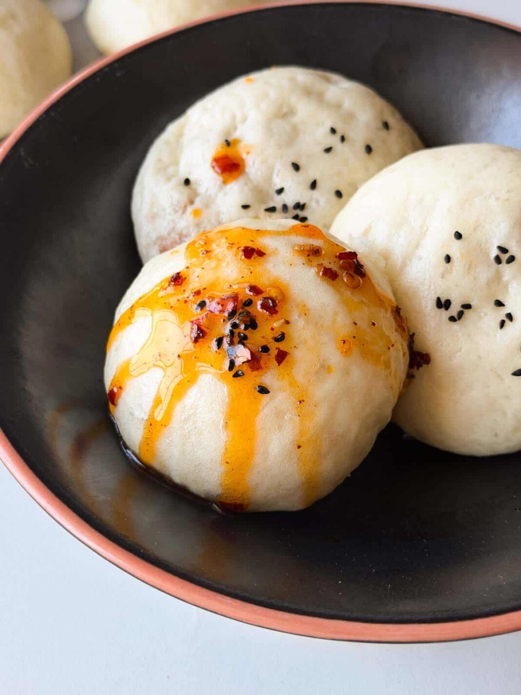 steamed buns or boazi served on a black plate with a drizzle of chilli oil
